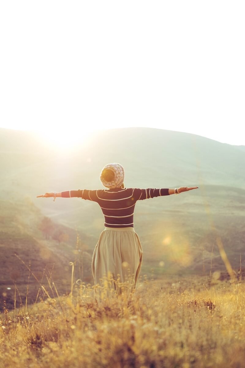 Photo by Pourya Sharifi woman with wide open arms standing on grass